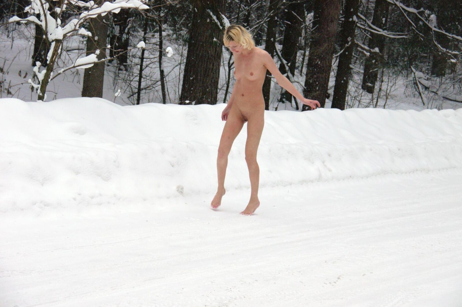 Junge Blondine pinkelt in den Schnee